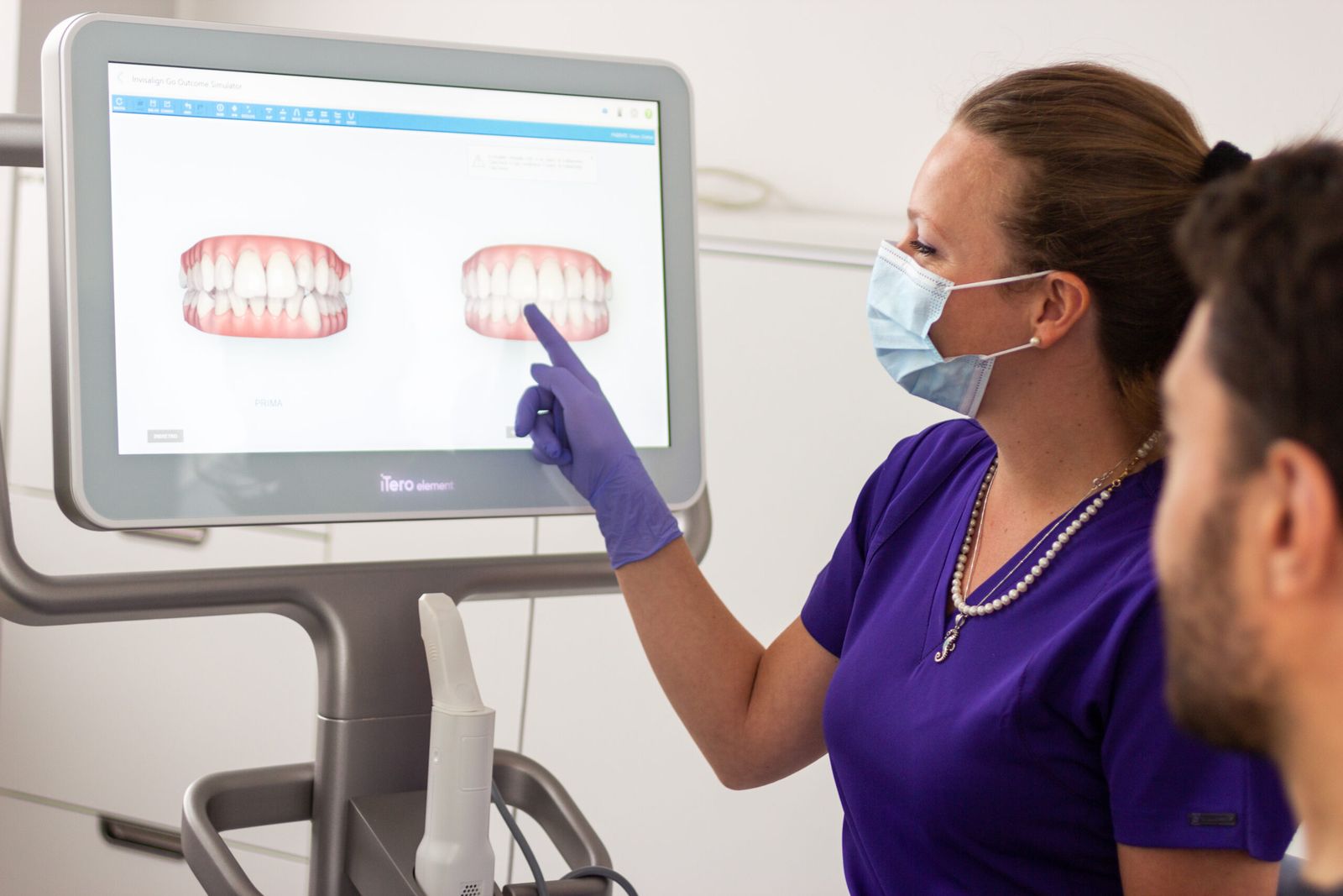 Un'assistente mostra a un paziente le immagini dei denti sullo schermo